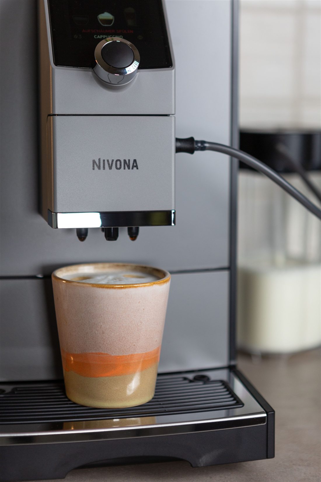 Kaffeevollautomat brüht einen frischen Cappuccino mit Milchschaum